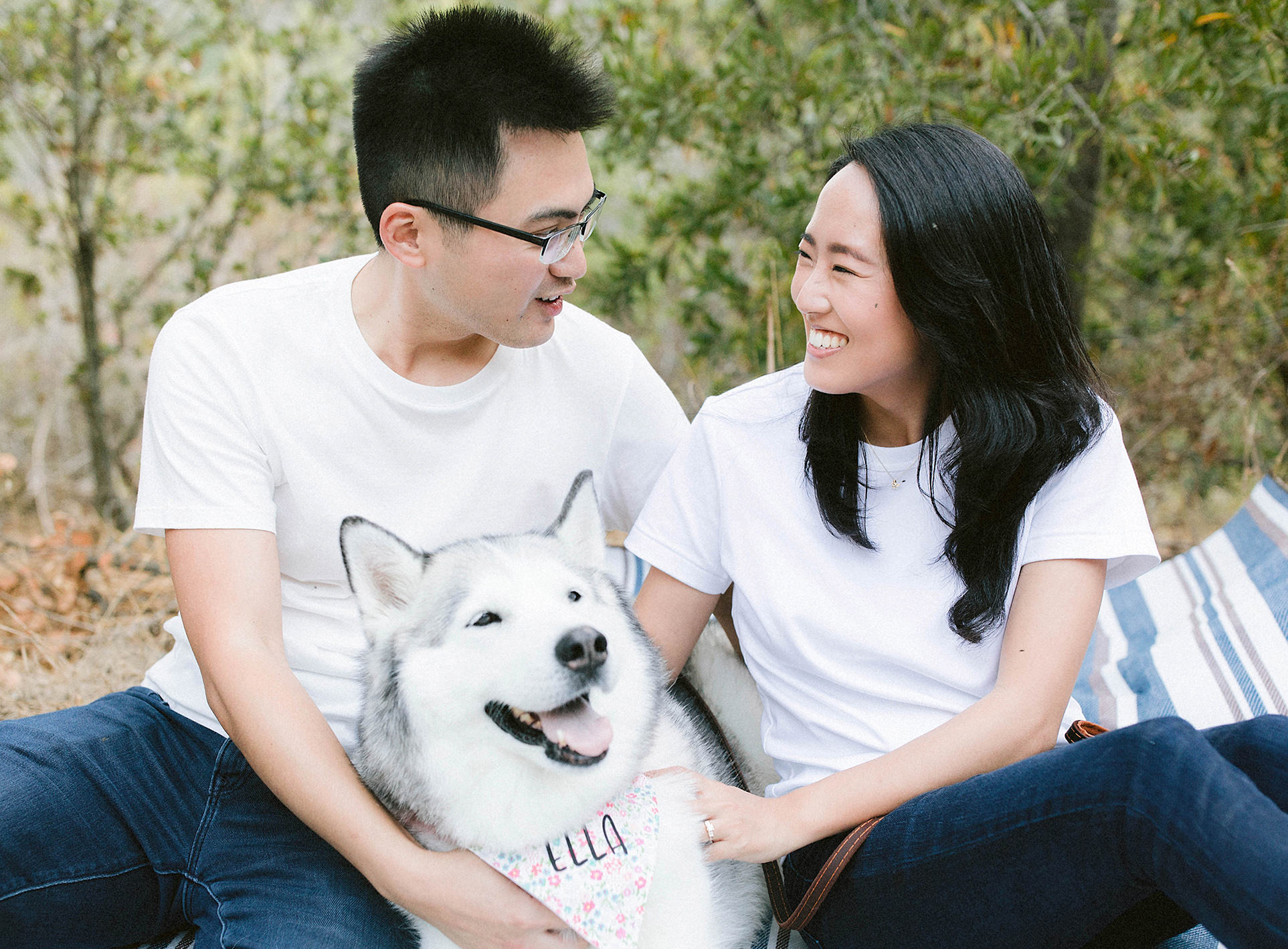 A Bay Area engagement photography session in Oakland with a couple smiling at each other with their Husky dog, Ella