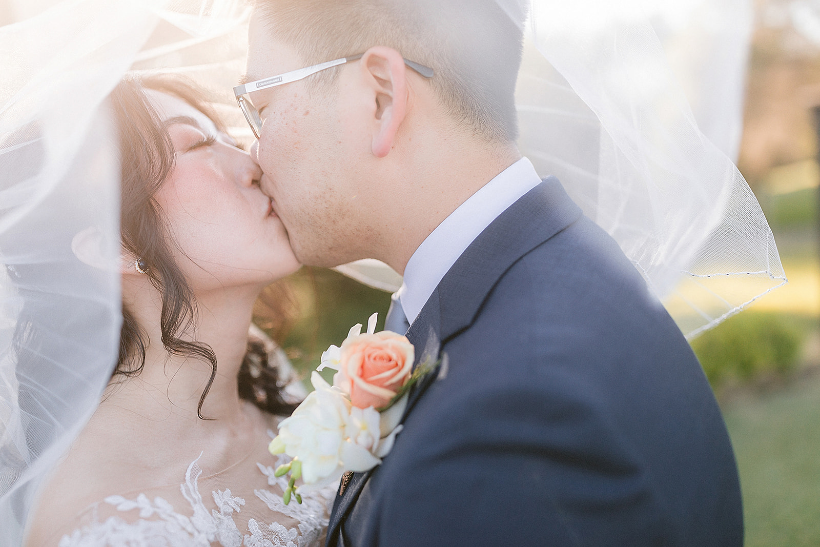 Bride and groom sharing a romantic kiss beneath the wedding veil during golden hour portraits at Hiddenbrooke Golf Club in Vallejo, California.